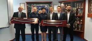 Na tle sztandaru komendy stoi Pani Komendant, jej Zastępca i czterech policjantów odchodzących na emeryturę. Dwóch z nich trzyma w rękach otrzymane szable.