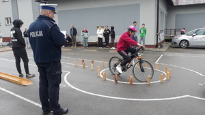 Policjant na torze przeszkód kontroluje przejazd jednego z uczestników zawodów.