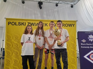 Czteroosobowa drużyna uczniów stoi na podium. W tle baner Polskiego Związku Motorowego i Komendy Głównej Policji.