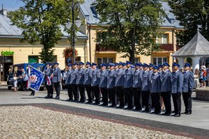 Na płycie rynku stoi pododdział policji wraz z pocztem sztandarowym