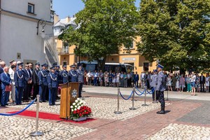 Dowódca uroczystości składa meldunek o zakończeniu apelu Zastępcy Komendanta Wojewódzkiego Policji w Krakowie. W tle zaproszeni gości i zgromadzeni  na rynku w Bieczu mieszkańcy miasta