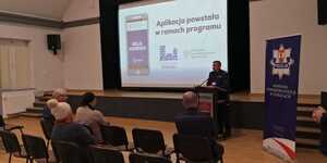 Na sali siedzą osoby, które słuchają wypowiedzi Policjanta.