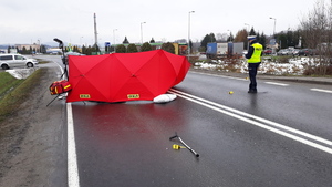 Obok parawanu na ulicy stoi policjant.